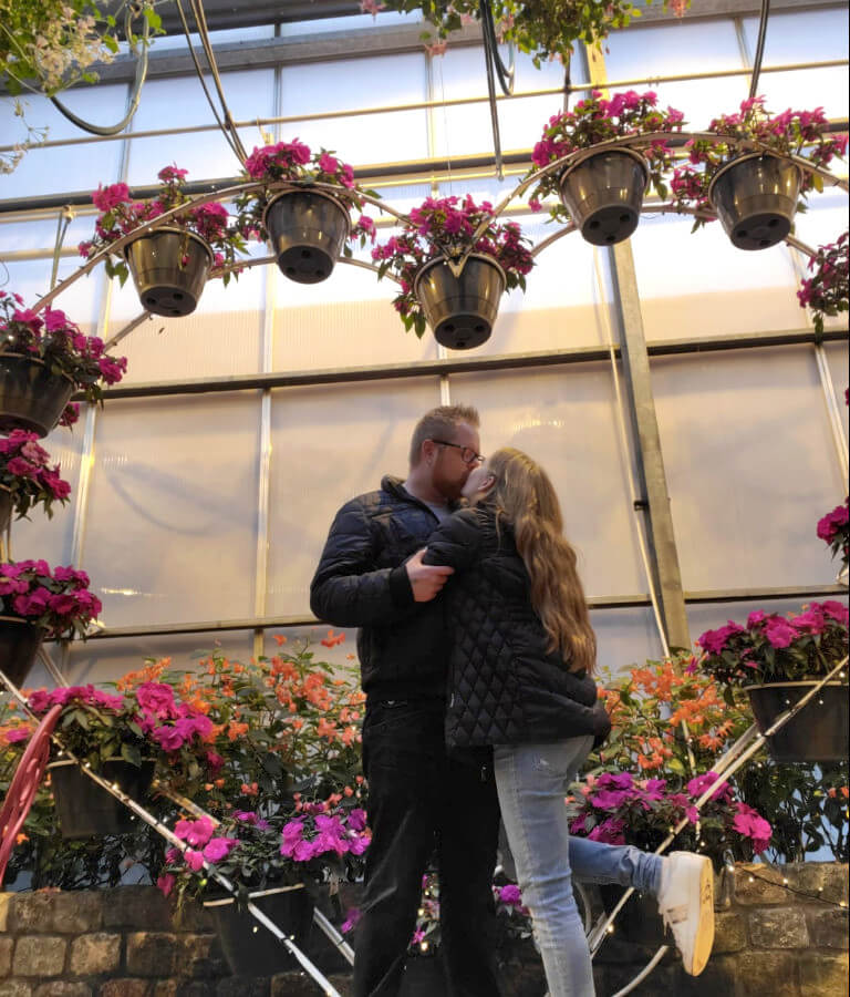 Isabelle and her husband Patrick kissing at a botanical garden